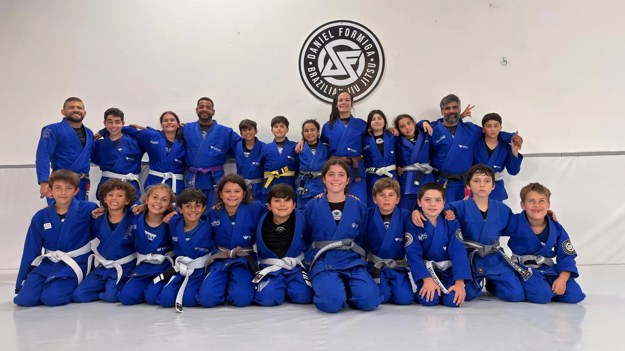 Equipa reunida no tatame, sob o logótipo Daniel Formiga BJJ